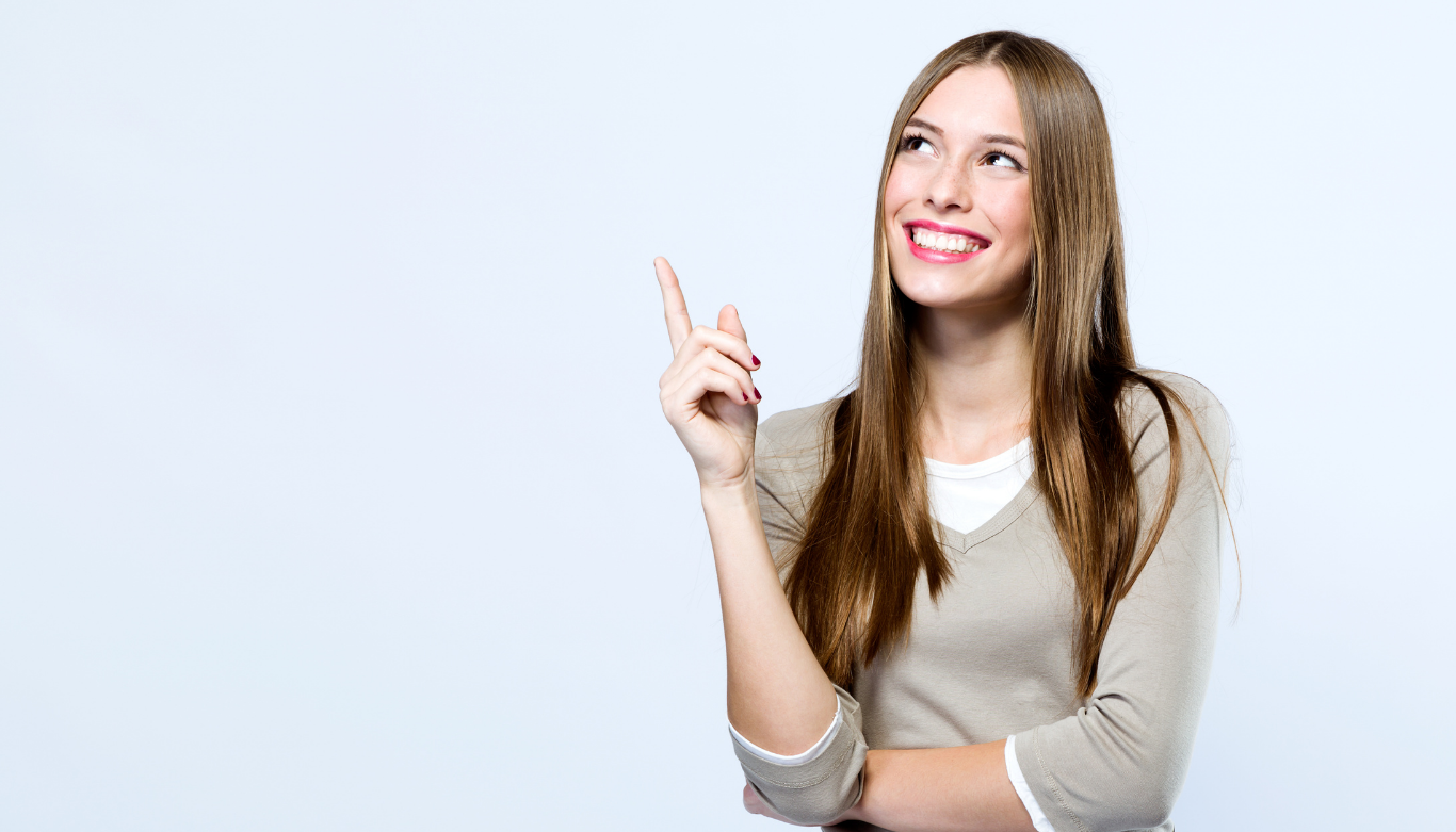 Smiling woman with long brown hair pointing upward with her index finger]